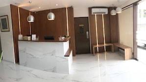 A hotel reception area with a marble counter, wooden paneling, and a bench. - Cebu R Hotel - Capitol (Cebu City)