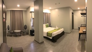 A hotel room with a bed, a small table with chairs, a mirror, and a coat rack. - Cebu R Hotel - Capitol (Cebu City)