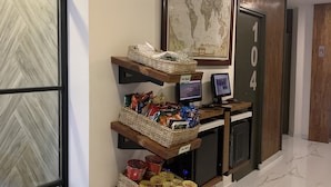 A hallway with a wooden floor, a world map on the wall, and shelves with snacks and a computer monitor. - Cebu R Hotel - Capitol (Cebu City)