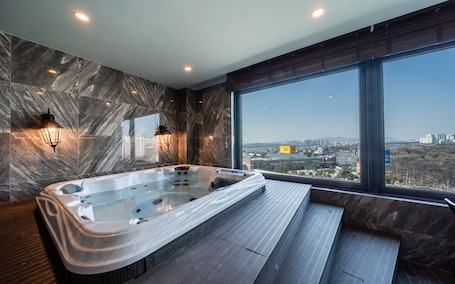 A modern bathroom with a large bathtub, marble walls, and a city view.. Partyz in Classic