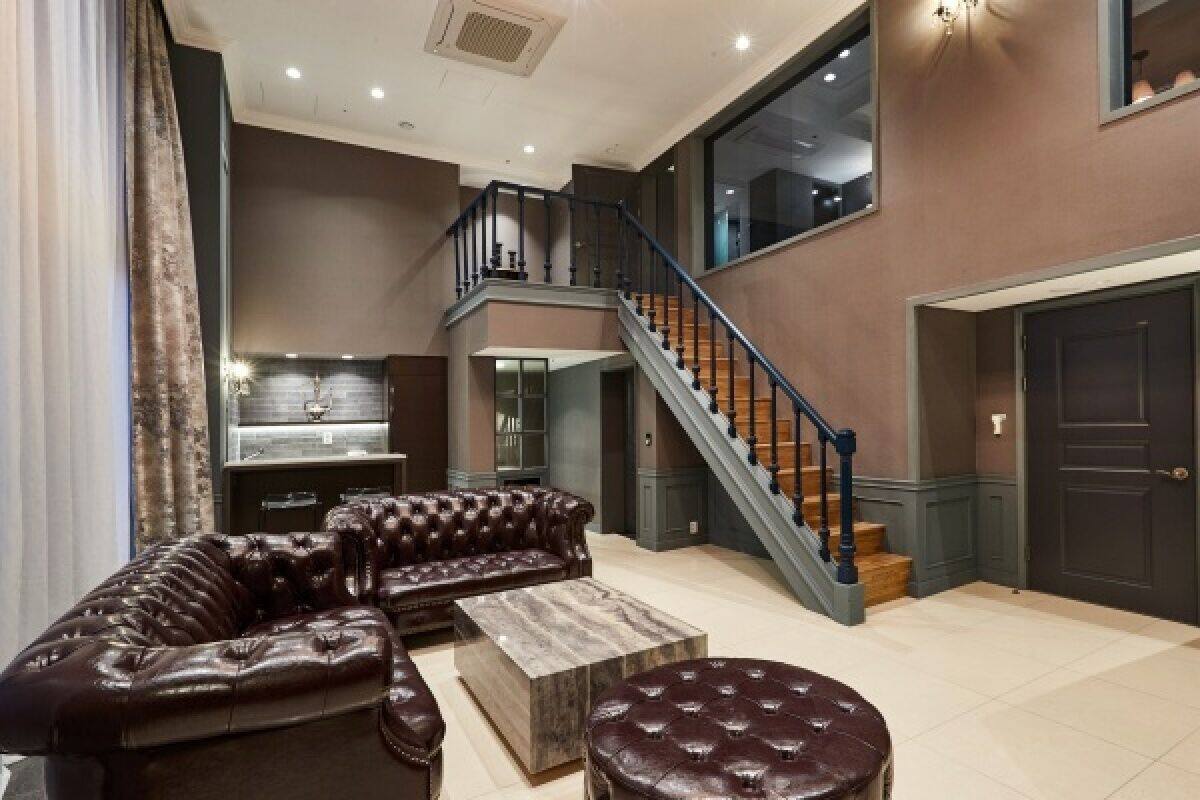 A spacious living area with a leather sofa, a coffee table, and a staircase leading to an upper floor.