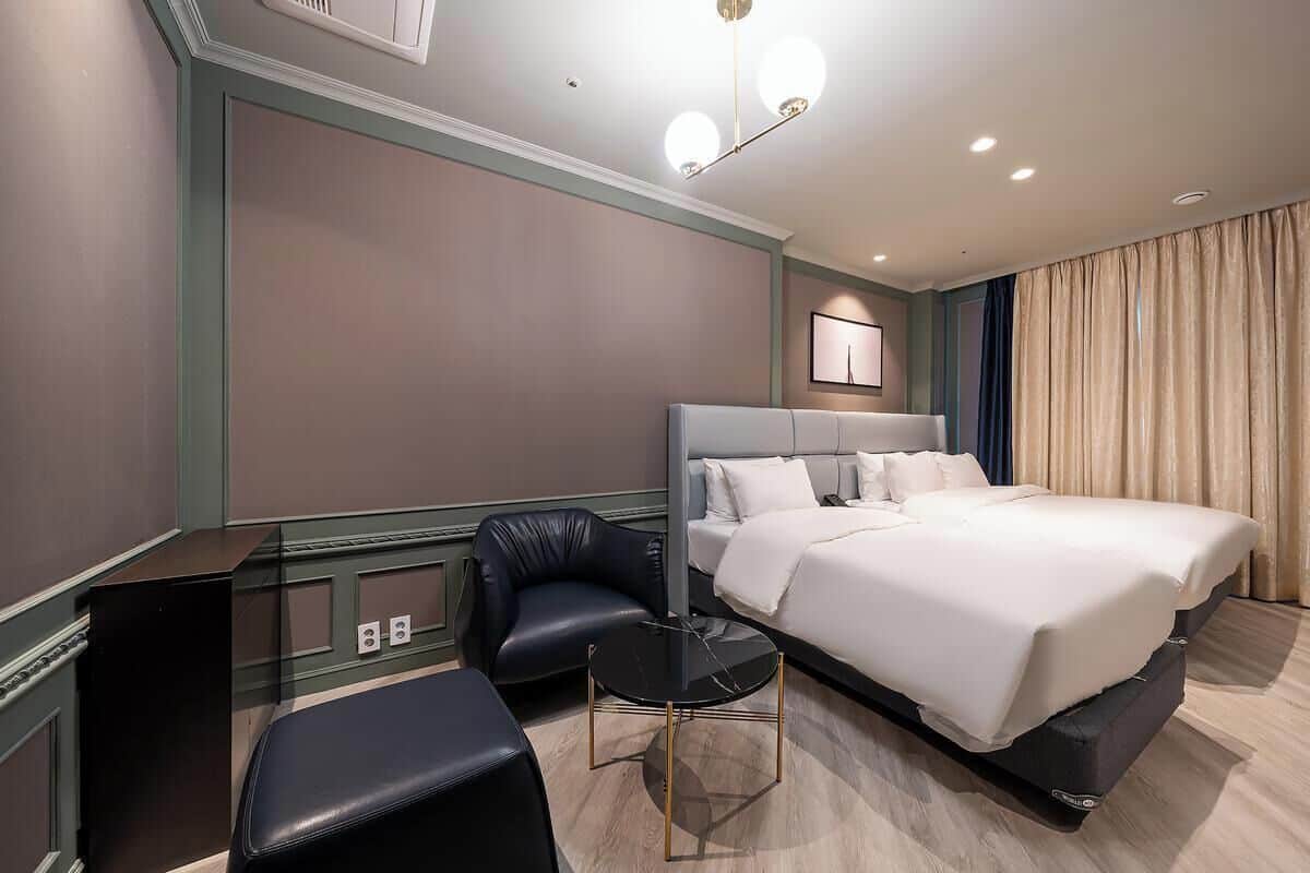 A hotel room with a large bed, a small round table, a chair, and a desk.