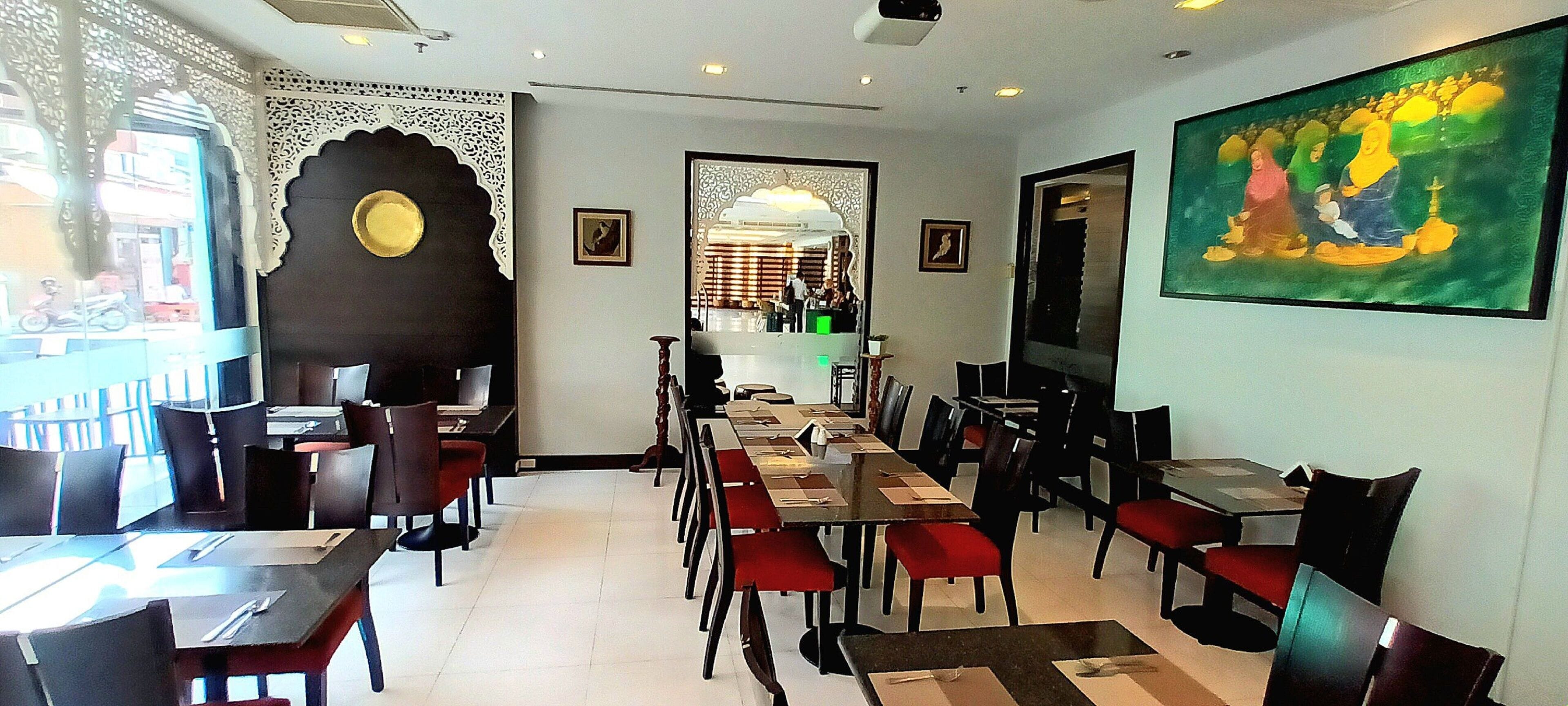 A restaurant with a long table and chairs, a decorative wall, and a painting.