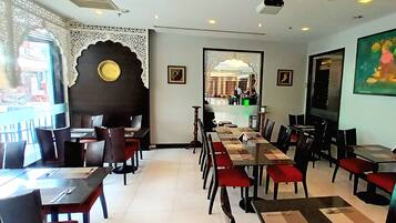 A restaurant with a long table and chairs, a decorative wall, and a painting.