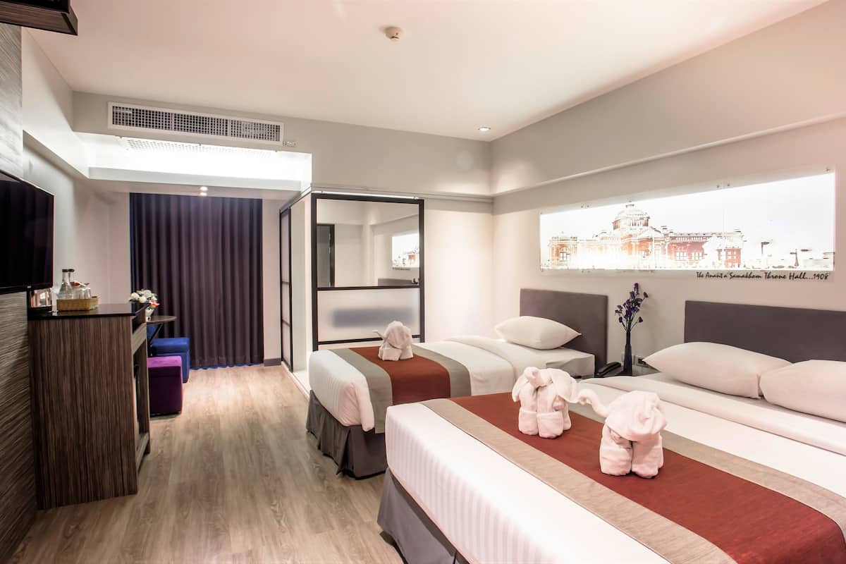 Een hotelkamer met een groot bed, een bureau, een flatscreen-tv, een spiegel en een raam met uitzicht op de stad.