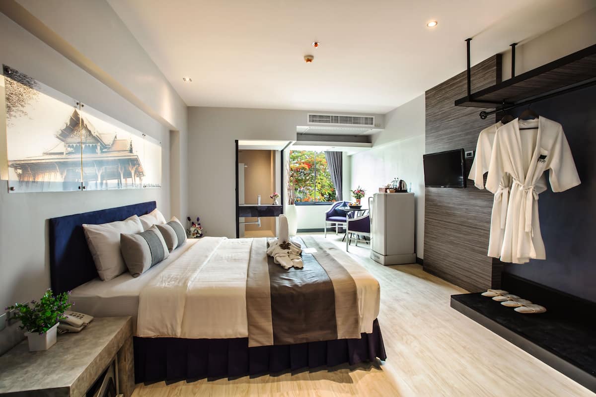 Een moderne hotelkamer met een groot bed, een televisie, een balkon met uitzicht en een kledingrek voor jassen.