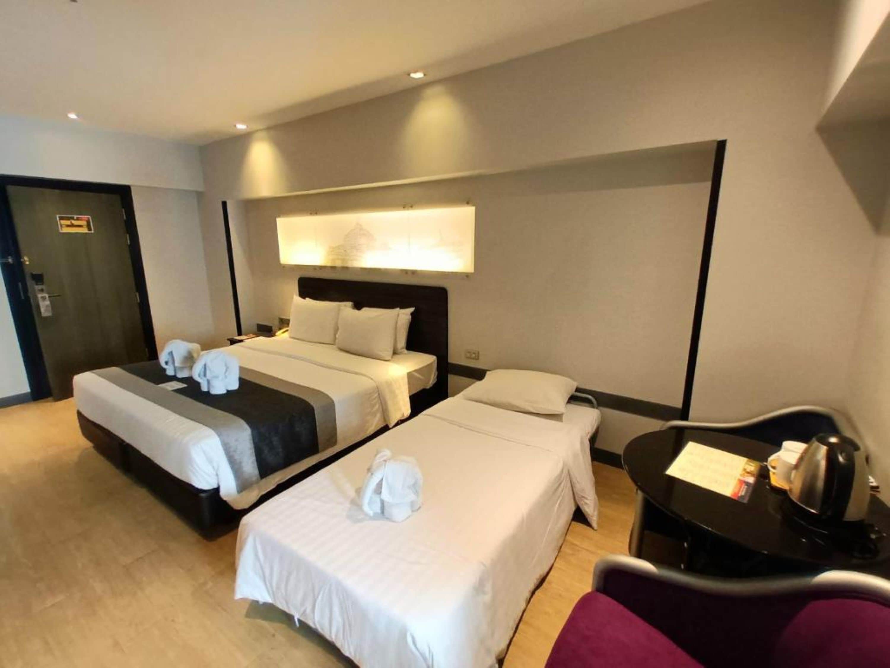 A hotel room with two beds, a desk, and a chair.