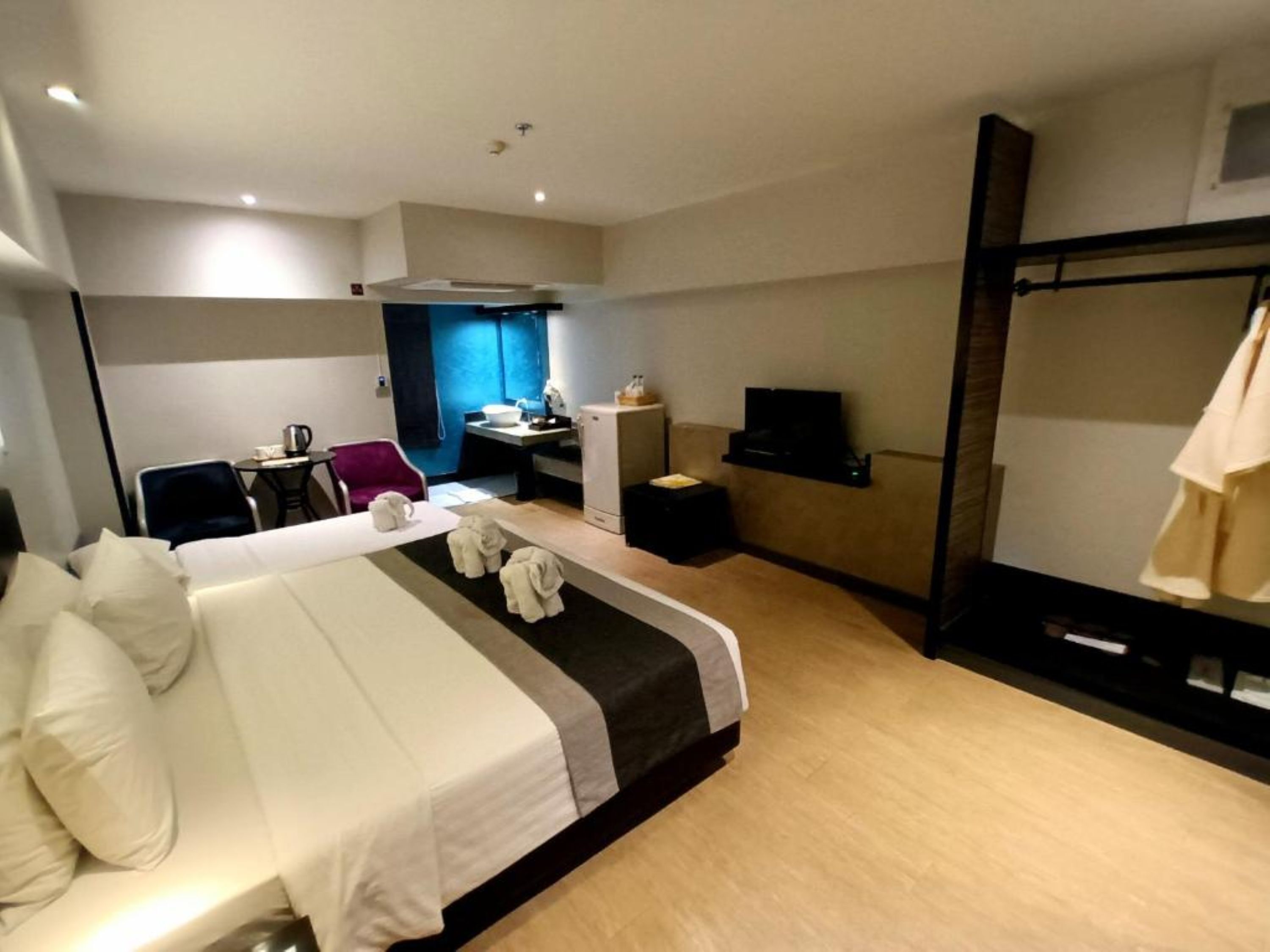 A hotel room with a bed, a desk, a chair, a TV, and a mirror.