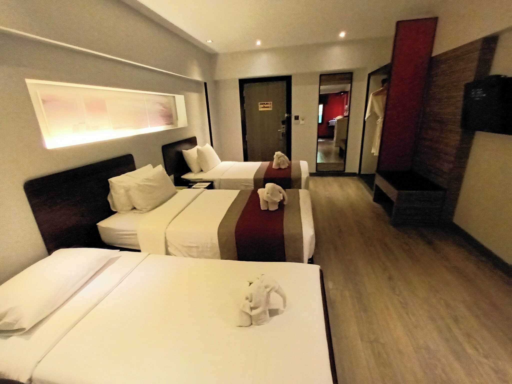 A hotel room with two beds, a TV, and a mirror.