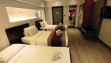 A hotel room with two beds, a TV, and a mirror.