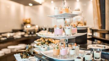 Un expositor de postres de varios niveles con diversos pequeños recipientes, incluyendo postres con frutas y un vaso con crema batida.
