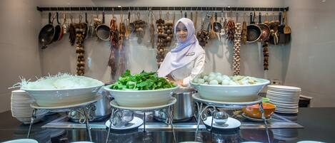 A buffet setup with various dishes and cooking utensils.