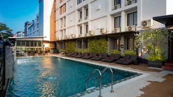 A rooftop pool with lounge chairs and a glass balustrade.