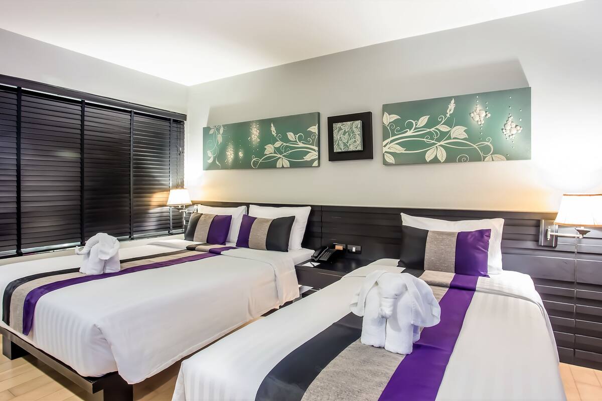 Een hotelkamer met twee bedden, een nachtkastje, een lamp en kunst aan de muur.