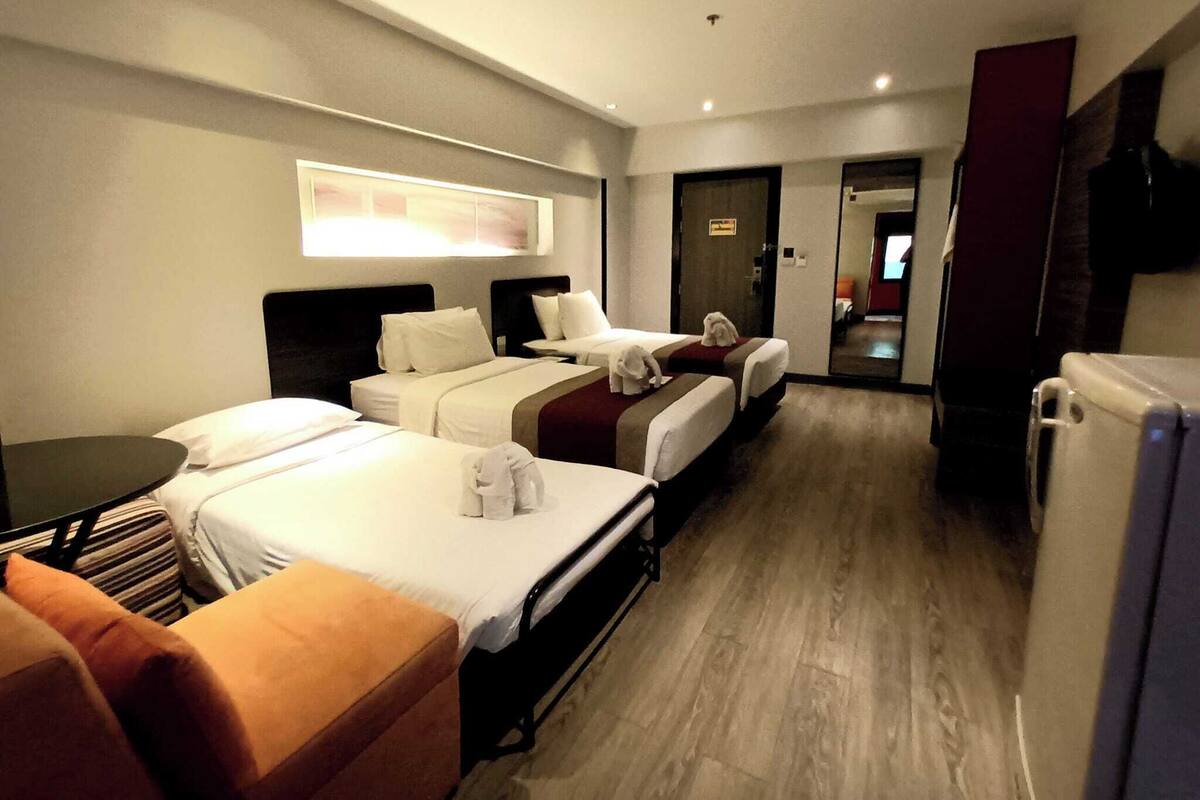 Een hotelkamer met twee bedden, een bureau, een stoel en een televisie.
