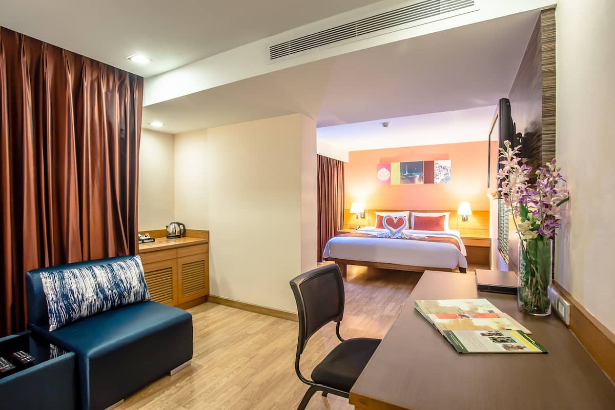 Een hotelkamer met een bed, een bureau, een stoel, een bank en een bloemenvaas.