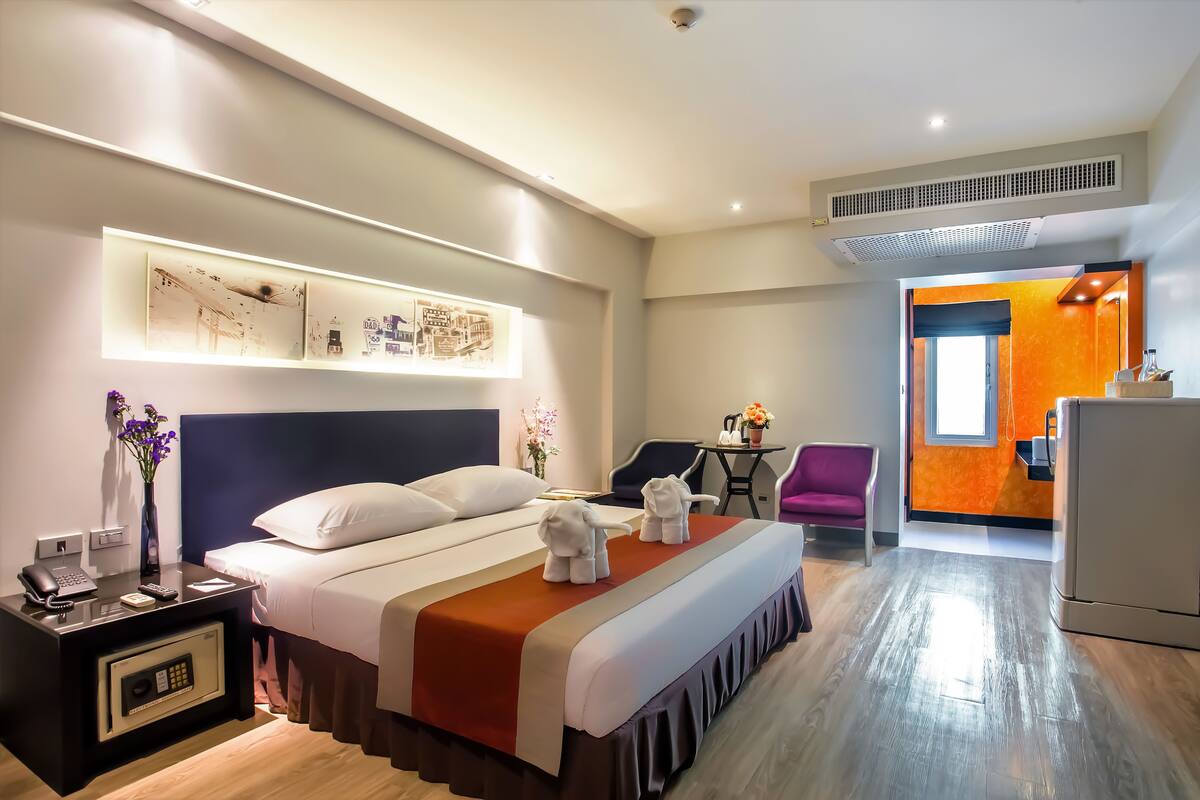 Een hotelkamer met een bed, nachtkastje, bureau en stoelen.