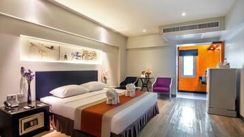 A hotel room with a bed, bedside table, nightstand, and a desk area with chairs.