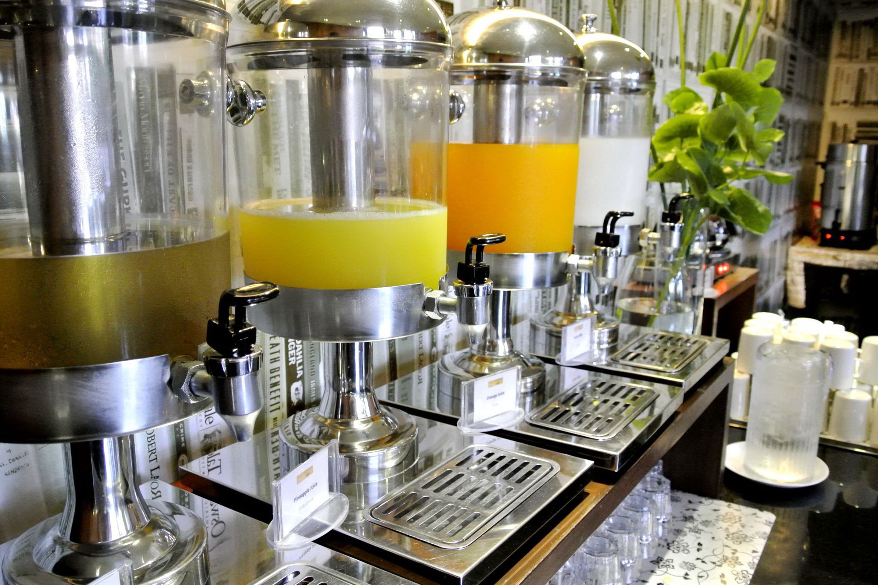 A bar area with multiple stainless steel dispensers, likely for beverages, and a variety of glassware on the counter.