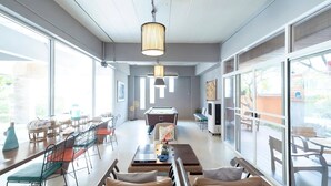 A spacious room with large windows, a pool table, and a seating area with chairs and tables. - Plai And Herbs Suvarnabhumi Airport (Bang Phli)