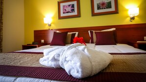 Una habitación de hotel con una cama grande, dos lámparas fijadas a la pared y dos cuadros enmarcados.