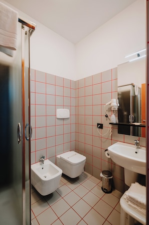 A bathroom with a bidet, toilet, sink, and a mirror.