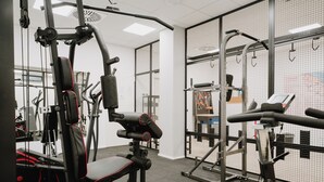 A gym with various exercise equipment, including a bench press, a squat rack, and a stationary bike. - Eden Hotel (San Salvo)