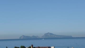 A coastal view with buildings, a lighthouse, and a distant mountain.