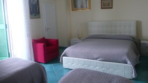 A bedroom with a bed, a red chair, a nightstand, and a door.