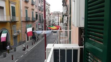 Une rue étroite bordée de bâtiments des deux côtés, avec des balcons et des unités de climatisation.
