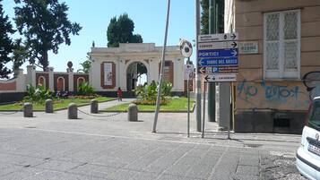 A street scene with directional signs, a building with an archway, and a parked car.