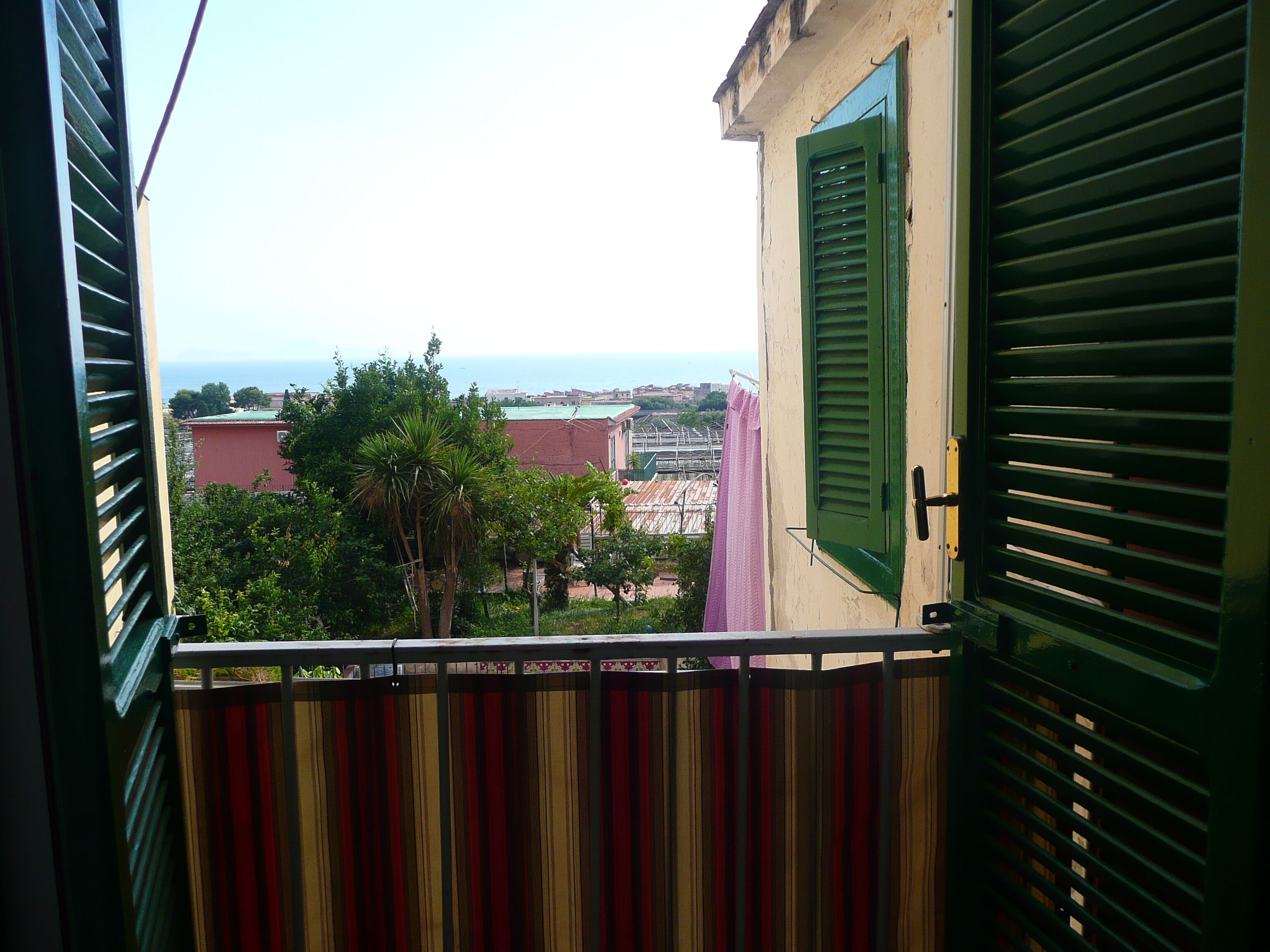 A balcony with a view of the sea and buildings.