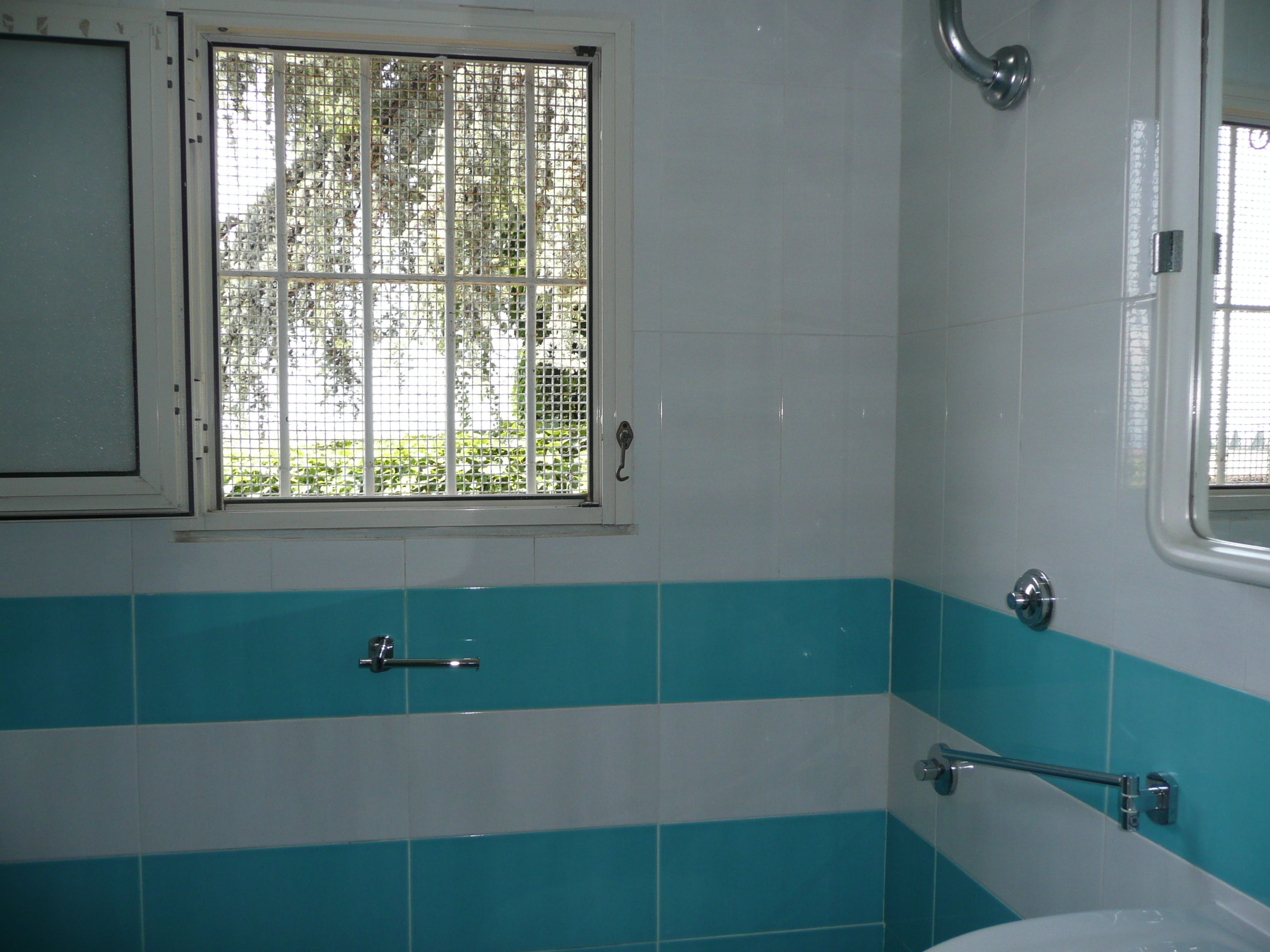 Een badkamer met raam, bad en toilet.