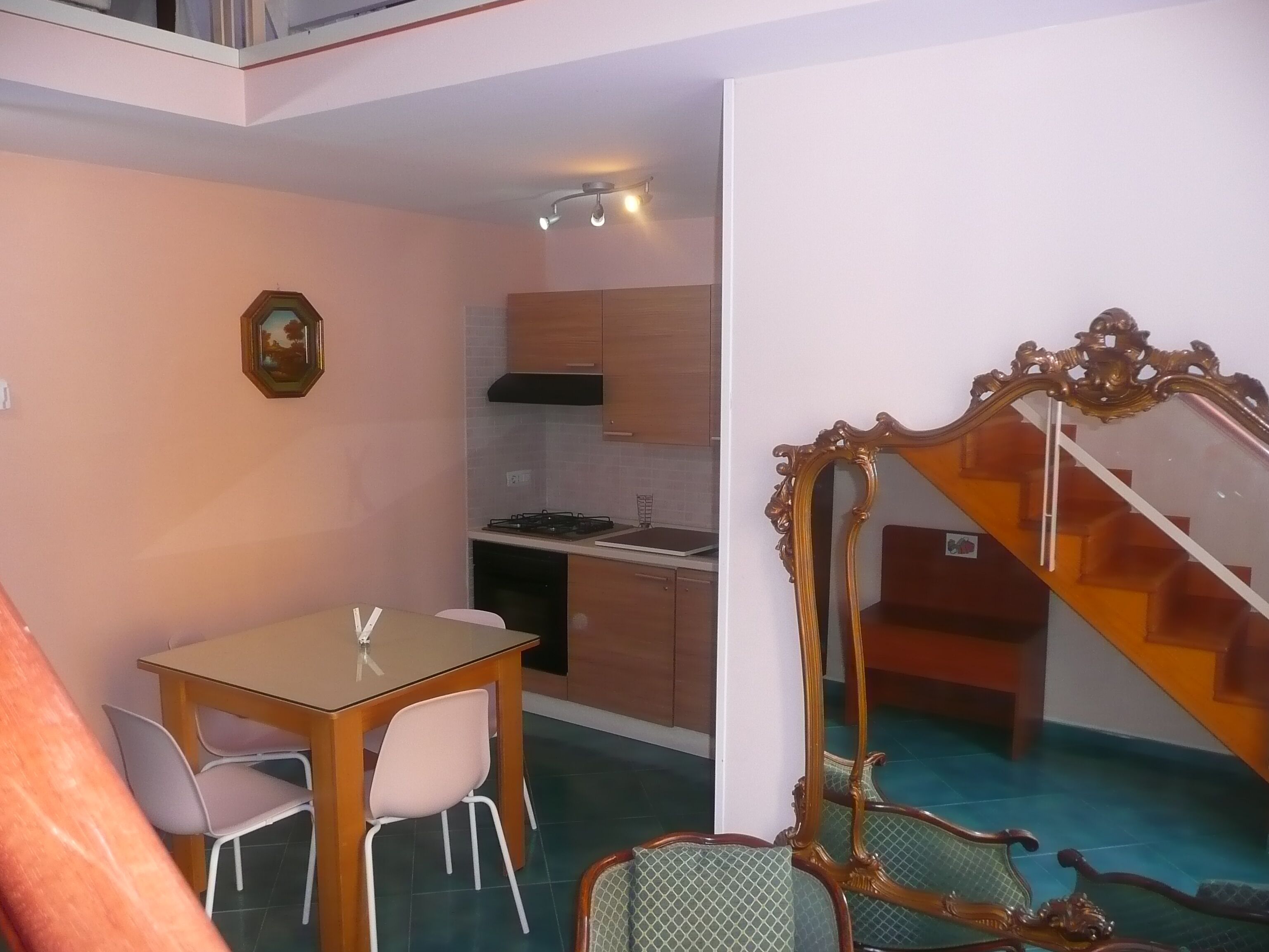A compact living space with a dining area, kitchenette, and a staircase.