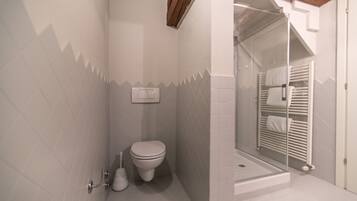 Un baño con inodoro, bidé y cabina de ducha de vidrio.
