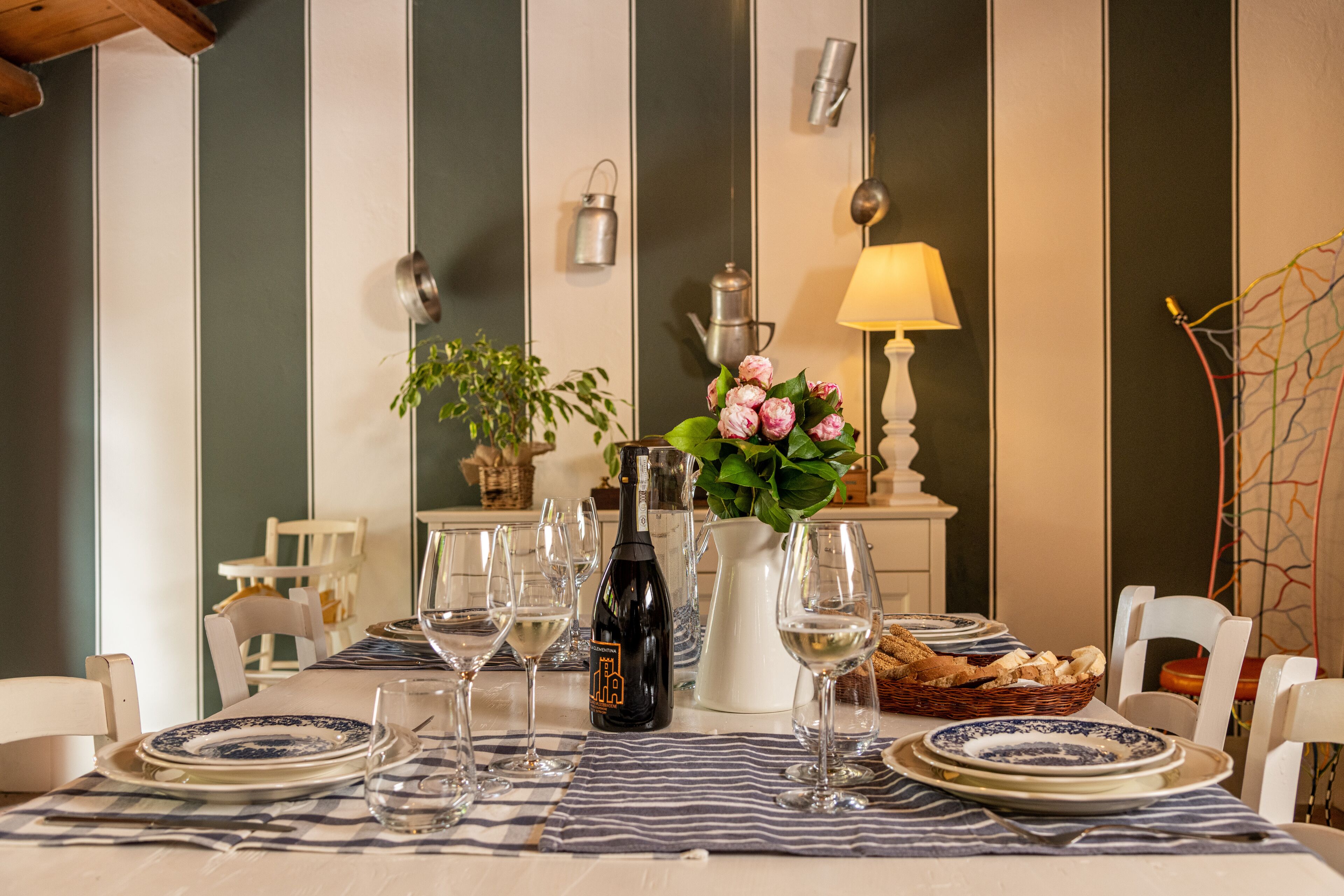 Une table à manger dressée avec des assiettes, des verres, une bouteille de vin et un panier de pain.