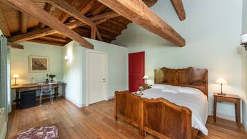 Une chambre à coucher avec un lit en bois, un bureau avec une chaise, une porte rouge et une petite table de chevet avec une lampe.