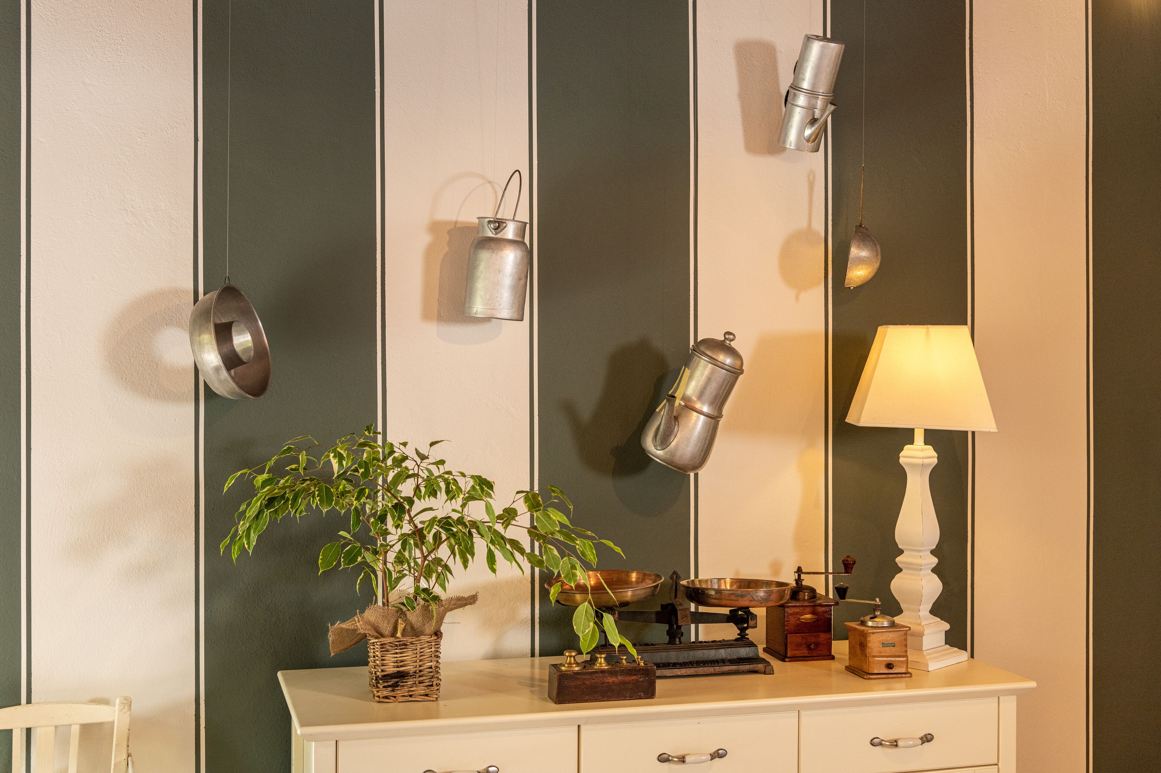 A bathroom with a mirror, a hanging light fixture, a potted plant, and a vintage-style lamp.