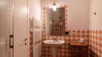A bathroom with a white door, a sink, a mirror, and a wooden cabinet.
