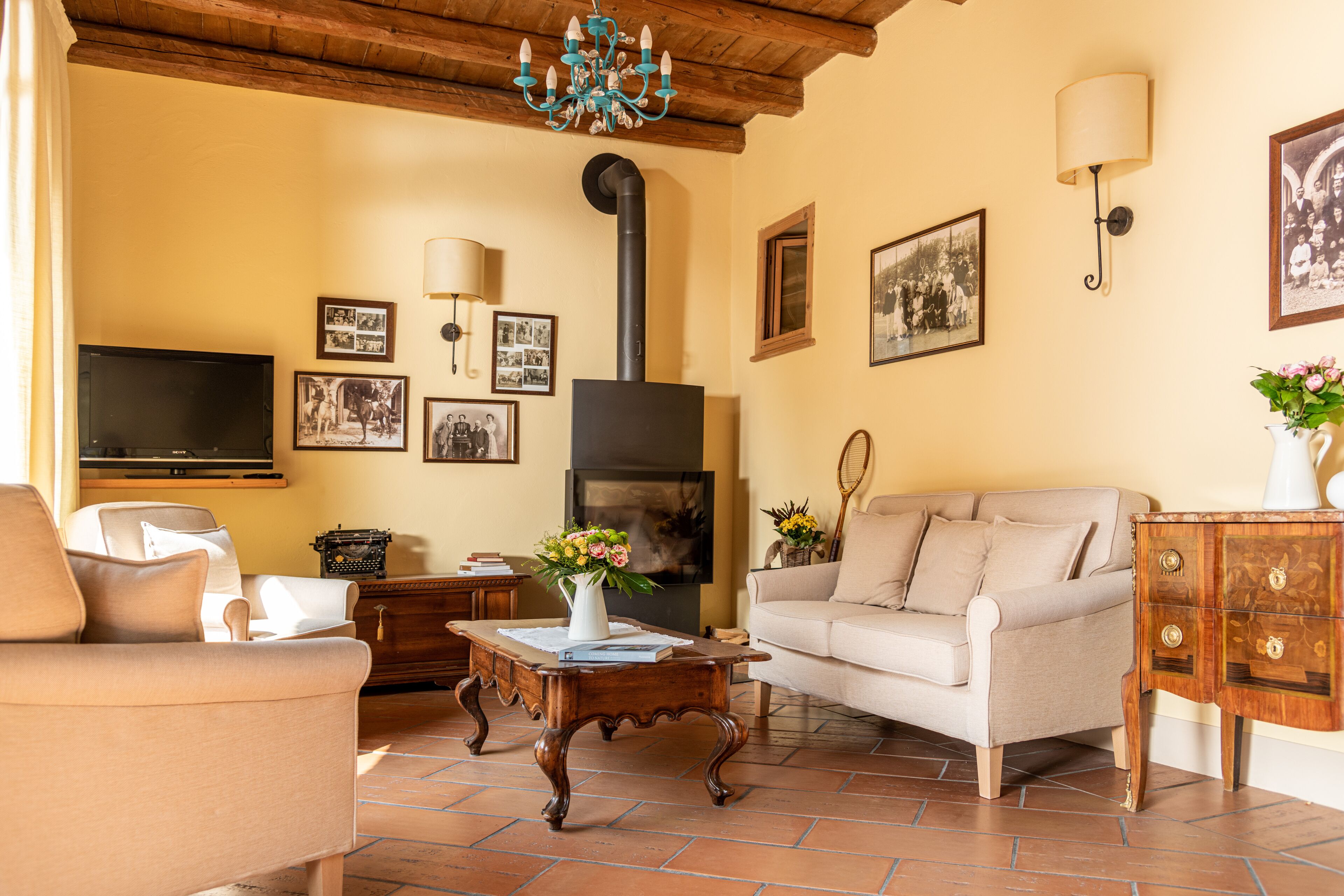 A living room with a sofa, a coffee table, a TV, a fireplace, and wall-mounted lamps.