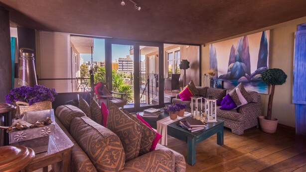 Un salón espacioso con un sofá grande, una mesa de centro y vistas de la ciudad a través de amplias ventanas.