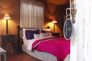 A bedroom with a bed, two bedside lamps, a nightstand, and a door with a keychain.