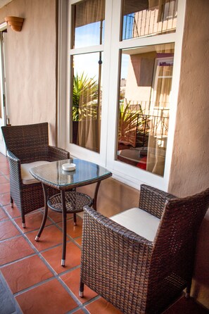 A patio with wicker furniture, a glass table, and a view through large windows.