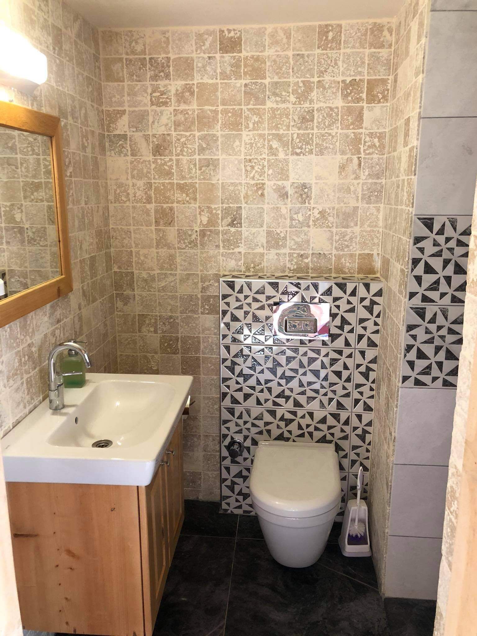 Un baño con lavamanos, espejo, inodoro y azulejos estampados.