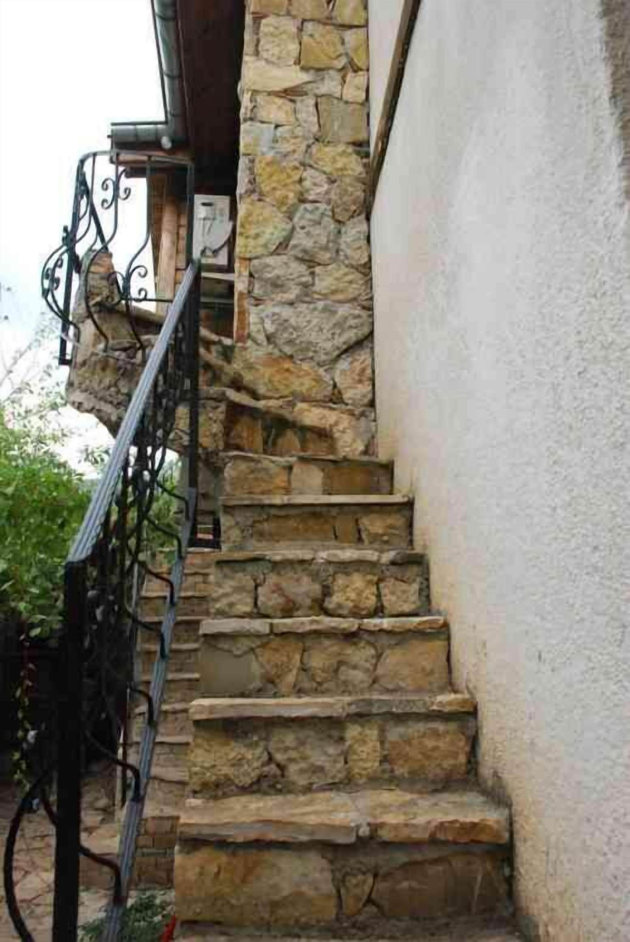 A stone staircase with metal railings leading to a door.
