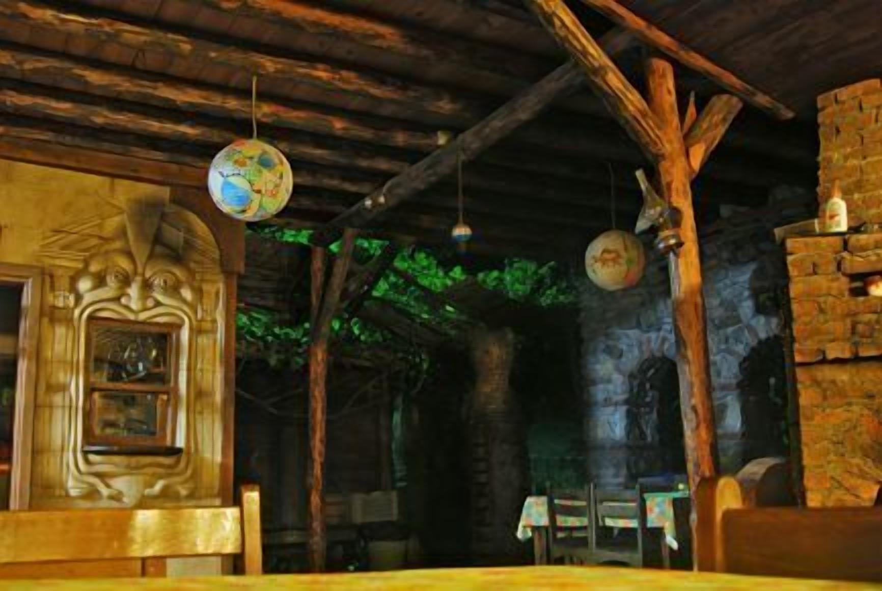 A rustic interior with exposed wooden beams, stone walls, and hanging globes.