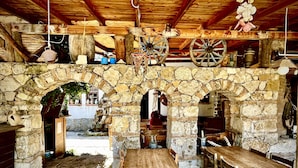 A rustic stone archway leading to a wooden dining area with tables and chairs.