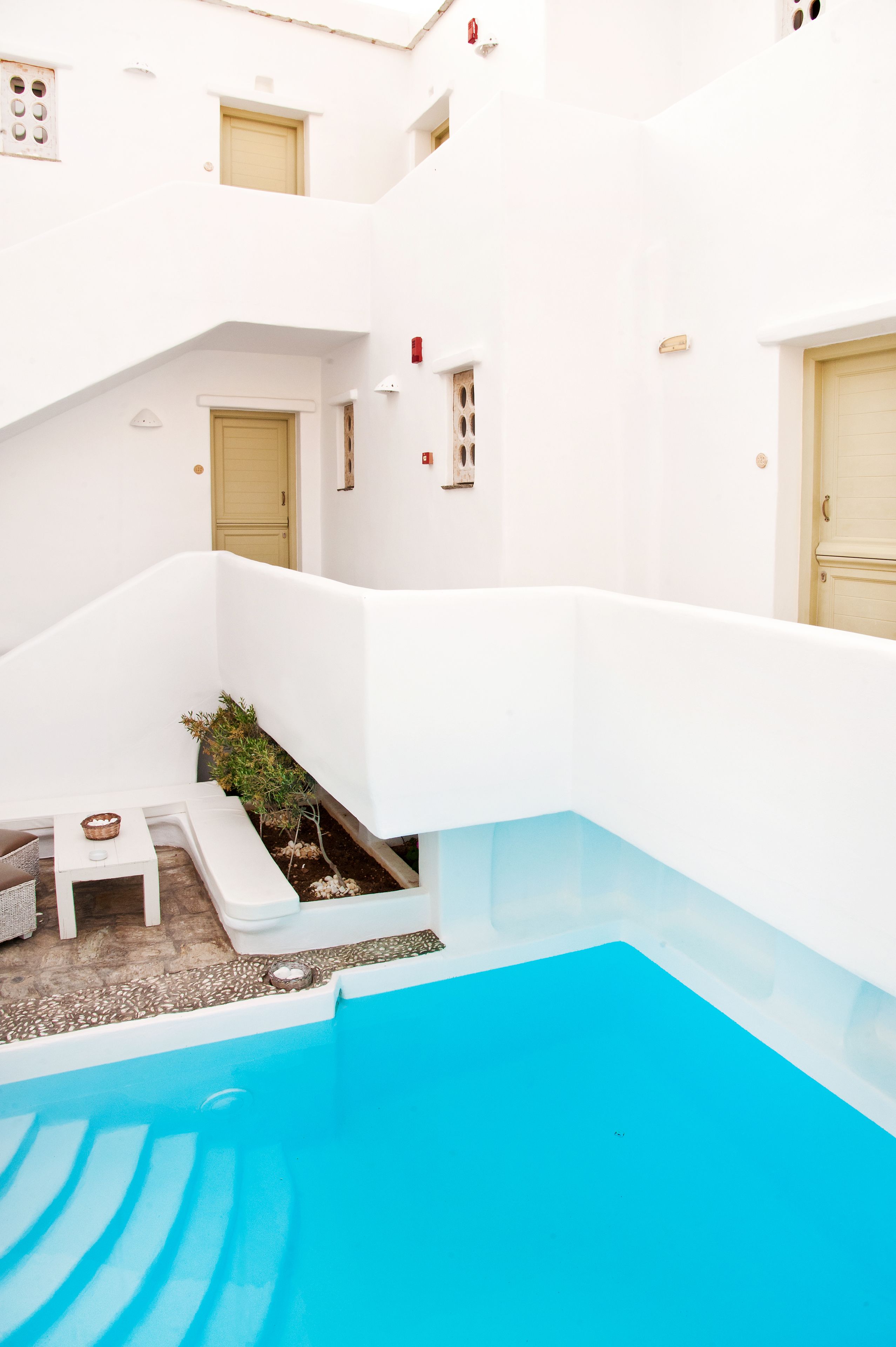 Un edificio blanco con piscina, una mesita y una planta.