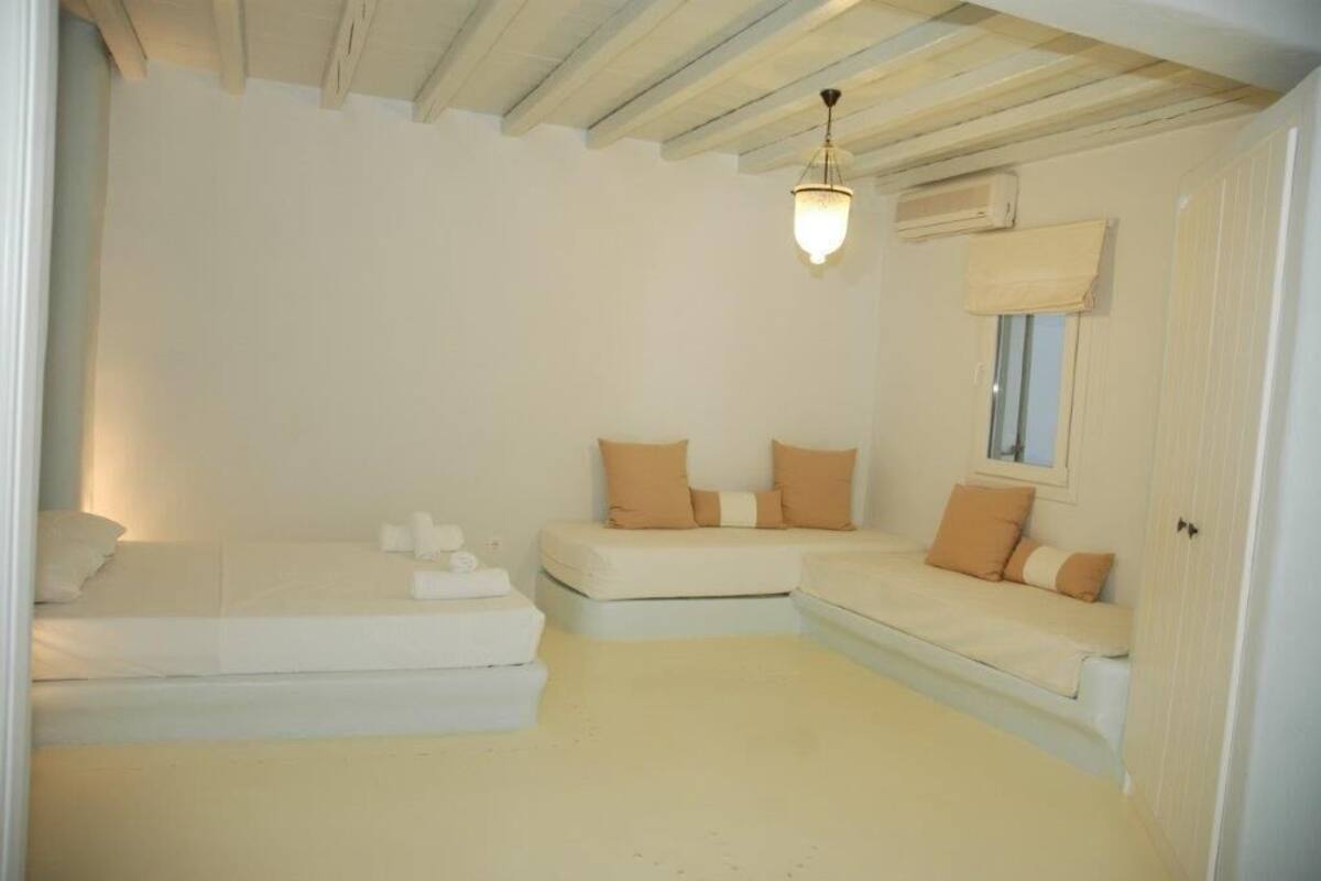 A minimalist bedroom with a white bed, a sofa, and a hanging light fixture.