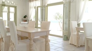 Un comedor luminoso con una mesa y sillas, ventanas amplias con cortinas y vistas al exterior.